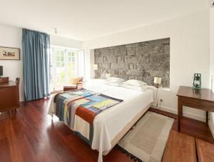 a bedroom with a large bed with a stone wall at Quinta das Buganvílias in Castelo Branco