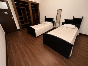 two beds in a room with wooden floors at Le coin vert in Rabat +1 photo