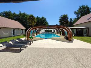 a swimming pool with lounge chairs and an arch around it at Domaine Sylvaria in Lassay-sur-Croisne