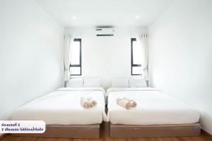 two beds in a room with white walls and windows at Amornrut Hill 03 in Ban Tao Than