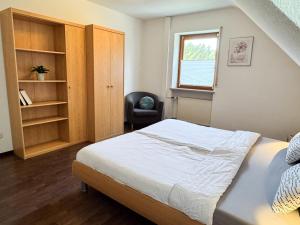 a bedroom with a bed and a chair at Ferienwohnung Weiher - Nähe Nürnberg / Messe in Schwanstetten