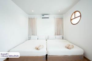 two beds in a room with white walls and a mirror at Amornrut Hill 03 in Ban Tao Than