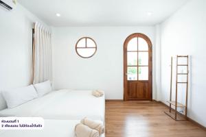 a white bedroom with a bed and a wooden door at Amornrut Hill 03 in Ban Tao Than