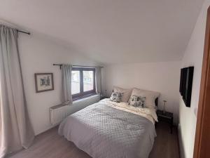 a white bedroom with a bed and a window at Apartmán Nádvorie in Levoča