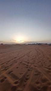a sunset in the desert with footprints in the sand at Sahara Starlight camp in Merzouga +3 photos