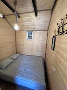 a bed in a small room in a wooden cabin at Domek Słoneczna in Mieroszyno