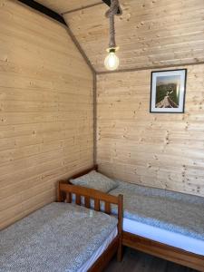 a room with two beds in a wooden cabin at Domek Słoneczna in Mieroszyno +5 photos