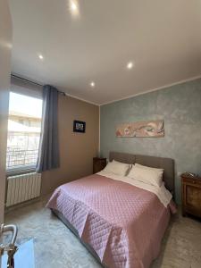 a bedroom with a bed with a pink blanket and a window at Rooms Vincanto in Salsomaggiore Terme