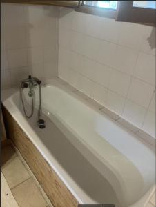 a white bath tub in a white tiled bathroom at La petite maison sur la colline in Rue