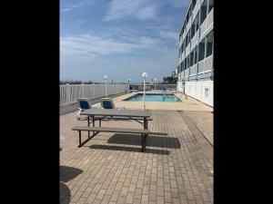 a picnic table and two chairs sitting next to a pool at Exceptional Ocean-Pier-Pool Front 1 BR Condo in Myrtle Beach