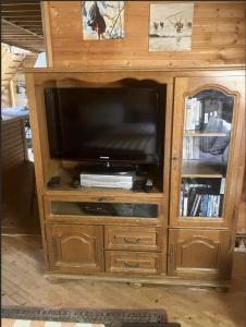 a wooden entertainment center with a flat screen tv at La petite maison sur la colline in Rue