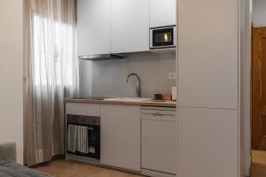 a small kitchen with white cabinets and a microwave at Casa del sol Armilla in Armilla