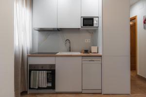 a kitchen with white cabinets and a sink and a microwave at Casa del sol Armilla in Armilla