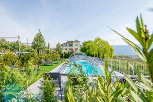 a glass bridge over a garden with a swimming pool at Quellenhof in Termeno