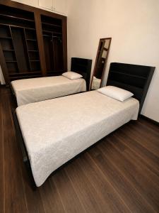 two beds in a room with wood floors at Le coin vert in Rabat