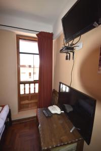 a living room with a desk with a television and a window at Fuente de Agua in Cusco