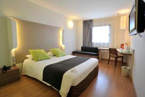 um quarto de hotel com uma cama grande e uma secretária em Campanile Málaga Airport em Málaga