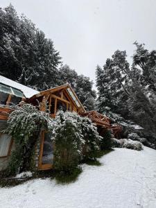 a house covered in snow with trees in the background at El Remanso del Lago in Villa La Angostura