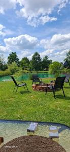 three chairs sitting in the grass near a pond at Cottage fairy in Dubrave Gornje