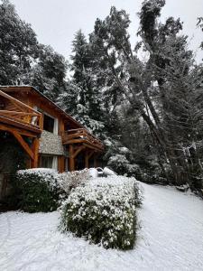 a house covered in snow in front at El Remanso del Lago in Villa La Angostura