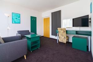 a room with a couch and a desk and a tv at Spa Sanatorium Dr Peták in Františkovy Lázně