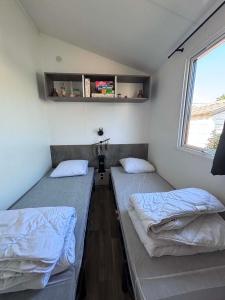 two twin beds in a room with a window at Camping Oléron Cap Soleil MH Climatisé in Saint-Denis-dʼOléron +35 photos
