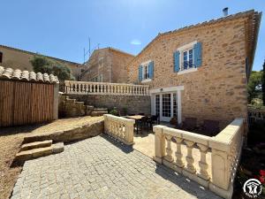 a stone house with a fence and a patio at Château de Prax Viel - piscine et mini ferme, climatisé in Lagrasse