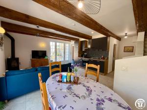 a kitchen and living room with a table and a blue couch at Château de Prax Viel - piscine et mini ferme, climatisé in Lagrasse
