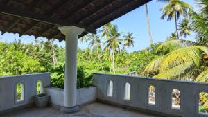 a view from the porch of a house with palm trees at Pedlar Bungalow in Talpe