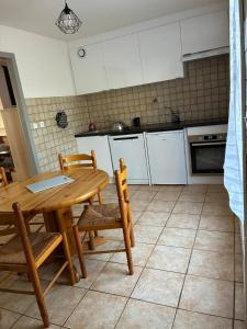 a kitchen with a wooden table and chairs and a kitchen with white cabinets at maison bozouls in Bozouls