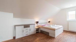 a white bedroom with a bed and a desk at Wellness apartmán Habánská in Pouzdřany
