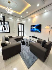 a living room with two couches and a flat screen tv at Western Suites in Douala