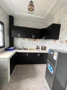 a kitchen with black cabinets and a stainless steel refrigerator at Western Suites in Douala +8 photos