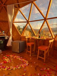 a room with a large window and a table with flowers on the floor at GLAMCAPTOUR in Guatavita