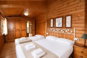 two beds in a room with wooden walls at Cabaña Las Cebras de Cabárceno in Penagos