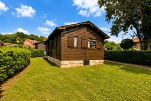 a small wooden house in a yard with a grass field at Cabaña Las Cebras de Cabárceno in Penagos