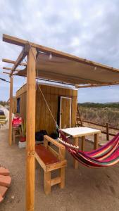 eine Hängematte und eine Hütte mit Tisch und Bank in der Unterkunft Solara Glamping in Tecate