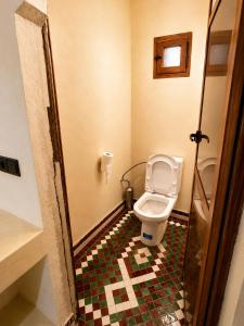 a bathroom with a toilet and a tiled floor at Camels House in Merzouga +28 photos