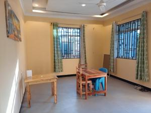 a room with a table and chairs and windows at Matui House in Kinyasini