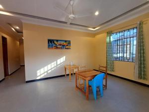 a dining room with two tables and a blue chair at Matui House in Kinyasini +5 photos