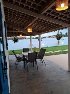 a table and chairs on a patio with a view of the water at Califeira do Patacho in Pôrto de Pedras