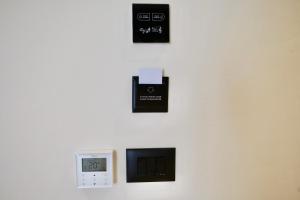 a wall with three switches and a clock on it at Zeo Hotel Saranda in Sarandë