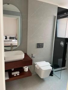 a bathroom with a sink and a toilet and a mirror at Zeo Hotel Saranda in Sarandë +26 photos