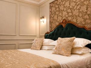 a bedroom with a bed with a green headboard and pillows at Lovelace Suites by Threads of Time Hotel Bruges in Bruges