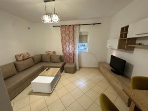a living room with a couch and a tv at Bledis Apartments in Lushnjë +2 photos