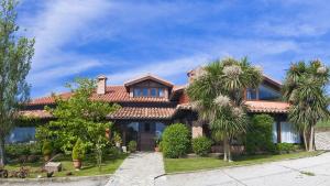 una casa con palmeras delante en La Posada de Langre, en Langre