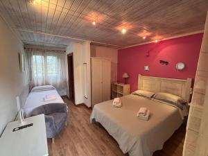 a bedroom with two beds and a red wall at Aldea del Trasgu in Cuerres