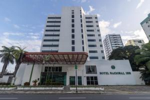 a tall white building with a sign in front of it at Hotel Nacional Inn Recife Aeroporto in Recife