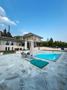a swimming pool with an umbrella and a table and chairs at Villa Seli in Dogliani