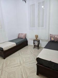 ein Schlafzimmer mit zwei Betten und einem Tisch darin in der Unterkunft Ariam in Annaba
